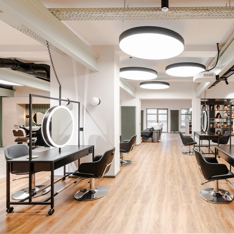 moderner-friseursalon-mit-heller-einrichtung-schwarzen-stühlen-großen-runden-spiegeln-und-holzboden-in-der-wild-beauty-akademie