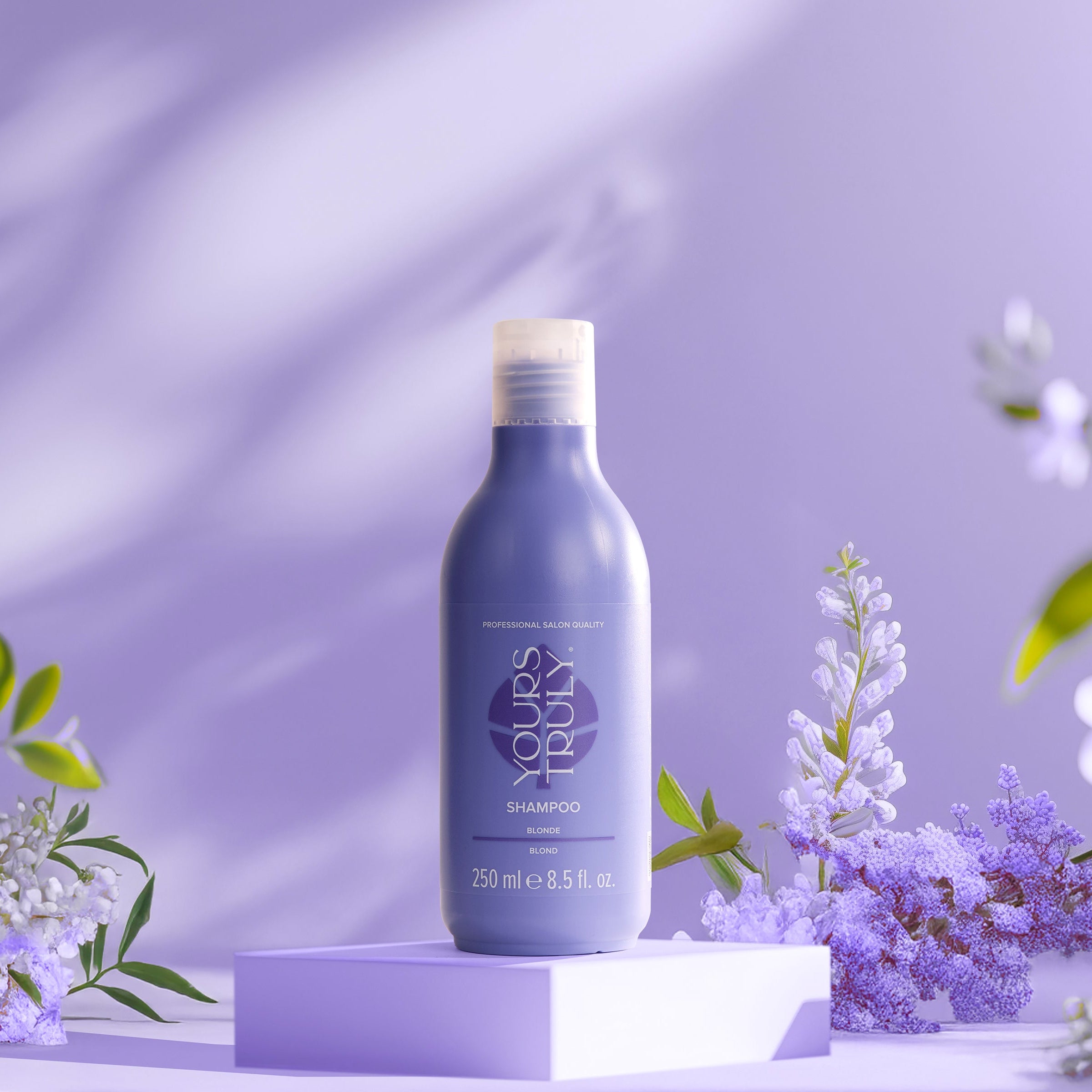 yours-truly-blonde-shampoo-in-lilaner-250ml-flasche-auf-podest-mit-lila-hintergrund-und-blühenden-lila-blumen
